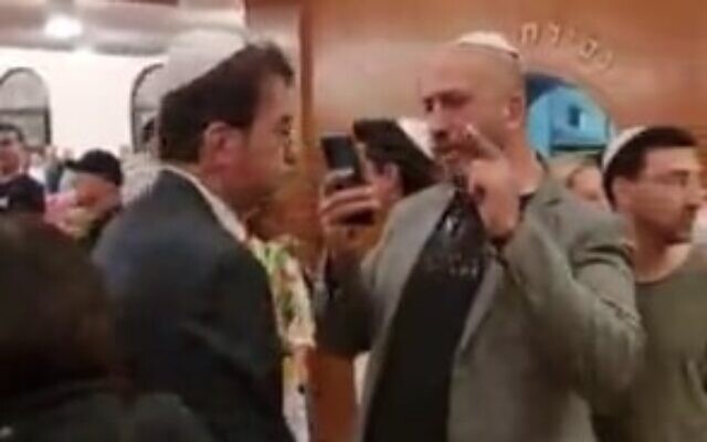 Le député du Likud Boaz Bismuth, à gauche, chahuté lors d'une cérémonie de commémoration de la Shoah, à Tel Aviv, le 17 avril 2023. (Crédit : Capture d'écran/Twitter)