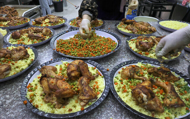 Crédit : Des cuisiniers employés par la Société caritative islamique préparent des portions du repas quotidien "iftar" (rupture du jeûne) pour les orphelins palestiniens et les familles dans le besoin, dans la ville d'Hébron en Cisjordanie, pendant le mois sacré musulman du Ramadan, le 12 avril 2022. (Crédit : Hazem Bader/AFP)