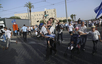 Des Israéliens courent vers des abris alors que les sirènes d'alerte aux roquettes retentissent lors du défilé pour la Journée de Jérusalem, le 10 mai 2021. (Crédit : Ariel Schalit/AP)