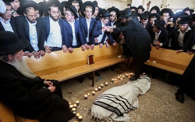 Des personnes en deuil se rassemblent autour du corps du rabbin Gershon Edelstein, l'un des chefs spirituels du judaïsme ultra-orthodoxe, avant ses funérailles à la Yeshiva Ponevezh à Bnei Brak, le 30 mai 2023. (Crédit : JACK GUEZ / AFP)