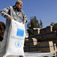 Un ouvrier palestinien décharge des denrées alimentaires données par l'Union européenne par l'intermédiaire du Programme alimentaire mondial et distribuées par l'Office de secours et de travaux des Nations unies (UNRWA) dans le village d'Arrabeh, près de Jénine, en Cisjordanie, le 26 décembre 2007. (Crédit : Mohammed Ballas/AP)