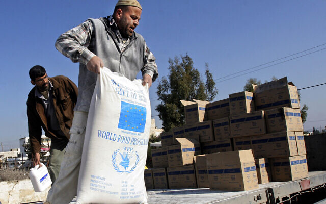 Un ouvrier palestinien décharge des denrées alimentaires données par l'Union européenne par l'intermédiaire du Programme alimentaire mondial et distribuées par l'Office de secours et de travaux des Nations unies (UNRWA) dans le village d'Arrabeh, près de Jénine, en Cisjordanie, le 26 décembre 2007. (Crédit : Mohammed Ballas/AP)