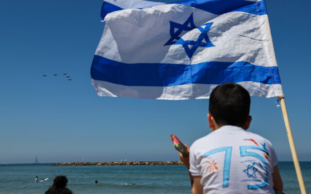 Des personnes regardent des avions de l'armée de l'air israélienne survoler une plage à Tel Aviv, le 26 avril 2023, à l'occasion du 75e anniversaire de la création de l'État d'Israël. (Crédit :rJack GUEZ / AFP)