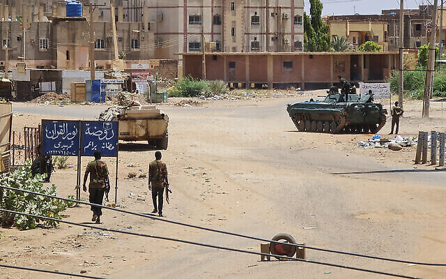Des soldats de l'armée soudanaise marchent à proximité de véhicules blindés stationnés dans une rue du sud de Kharoum, le 6 mai 2023. (Crédit :  AFP)