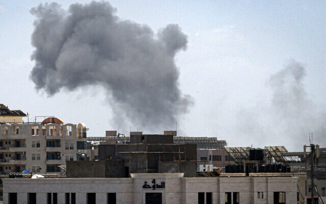 Un panache de fumée s’élèvant au-dessus d'un bâtiment après une frappe aérienne israélienne dans la ville de Gaza le 13 mai 2023, au milieu des combats entre Israël et le Jihad islamique palestinien. (Crédit : Mahmud Hams/AFP)