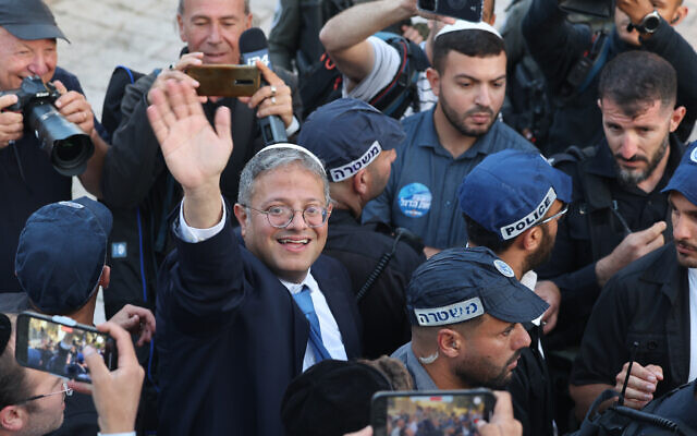 Le ministre de la Sécurité nationale, Itamar Ben Gvir, entouré d'officiers de police, salue les personnes rassemblées devant la porte de Damas menant à la Vieille Ville de Jérusalem, le 18 mai 2023. (Crédit : AHMAD GHARABLI / AFP)