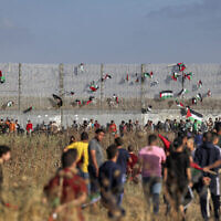 Des drapeaux palestiniens sont accrochés à la barrière de sécurité d’Israël lors d’une manifestation le long de la frontière avec Israël, à l’Est de Gaza, le 18 mai 2023, en réaction à la marche annuelle du drapeau israélien, en l'honneur du Jour de Jérusalem (Crédit : Mohammed ABED / AFP)