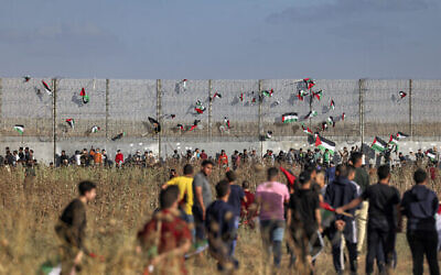 Des drapeaux palestiniens sont accrochés à la barrière de sécurité d’Israël lors d’une manifestation le long de la frontière avec Israël, à l’Est de Gaza, le 18 mai 2023, en réaction à la marche annuelle du drapeau israélien, en l'honneur du Jour de Jérusalem (Crédit : Mohammed ABED / AFP)