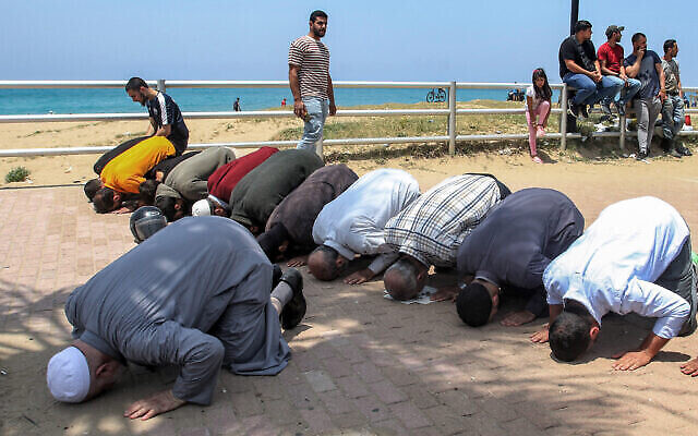 Des hommes musulmans prient le long d'un trottoir près d'une plage publique après une manifestation contre les coutumes de pudeur, dans la ville de Sidon, au sud du Liban, le 21 mai 2023. (Crédit : MAHMOUD ZAYYAT/AFP)