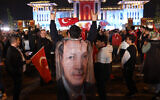 Un partisan du président turc Recep Tayyip Erdogan porte un drapeau à son effigie sur ses épaules et fait le Bozkurt isareti (salut du loup gris), un symbole nationaliste turc et pan-turc de la main, alors que les gens célèbrent sa victoire au second tour de l'élection présidentielle, devant le palais présidentiel d'Ankara, le 29 mai 2023. (Crédit: Adem ALTAN / AFP)