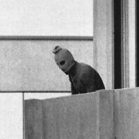 Un membre de l'organisation terroriste qui a attaqué des membres de l’équipe olympique israélienne dans l'enceinte du Village olympique, encagoulé,  se tient sur le balcon du bâtiment où ont été retenus en otage les membres de l’équipe israélienne à Munich, le 5 septembre 1972. (Crédit : AP/Kurt Strumpf)