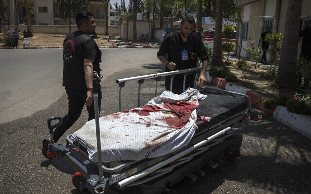 Des secouristes palestiniens tirant une civière ensanglantée après des frappes aériennes israéliennes, à Khan Younis dans la Bande de Gaza, le 10 mai 2023. (Crédit : AP Photo/Fatima Shbair)