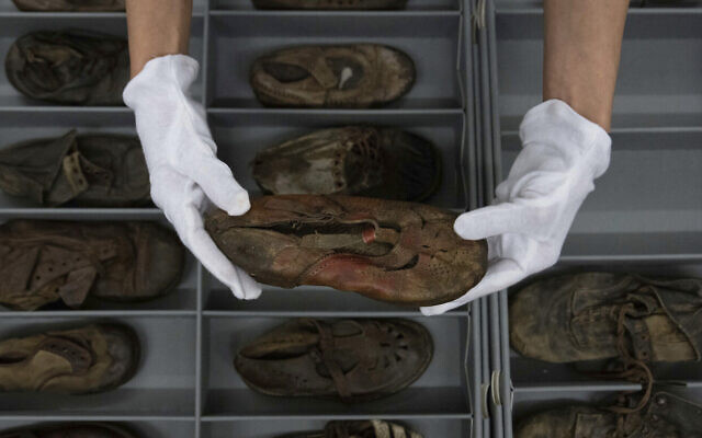 Elzbieta Cajzer, responsable du département des collections du musée, montre une collection de chaussures ayant appartenu à des enfants victimes de l'ancien camp de la mort nazi d'Auschwitz-Birkenau au laboratoire de conservation sur son terrain, à Oswiecim, Pologne, le 10 mai 2023. (Crédit : AP Photo /Michal Dyjuk)