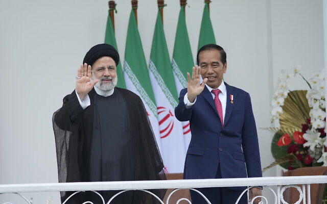 Le président iranien Ebrahim Raisi, à gauche, et le président indonésien Joko Widodo, à droite, saluent les journalistes lors de leur rencontre au palais présidentiel de Bogor, en Indonésie, le 23 mai 2023. (Crédit : Achmad Ibrahim/AP)