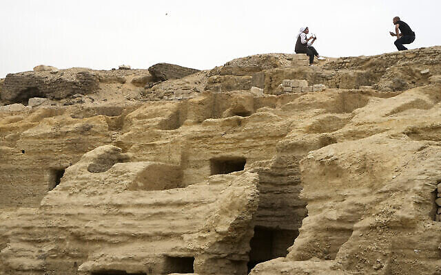 Des visiteurs posant pour des photos au-dessus d'anciens ateliers d'embaumement récemment mis au jour sur le site de la pyramide à degrés de Djéser, à Saqqara, en Égypte, le 27 mai 2023. (Crédit : AP Photo/Amr Nabil)