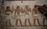 Un archéologue égyptien montrant une peinture colorée d'une offrande de sacrifice dans une tombe récemment découverte qui aurait appartenu à un haut fonctionnaire de la 5e dynastie appelé "Ne Hesut Ba" (2 400 avant notre ère), sur le site de la pyramide à degrés de Djéser, à Saqqara, en Égypte, le 27 mai 2023. (Crédit : AP Photo/Amr Nabil)