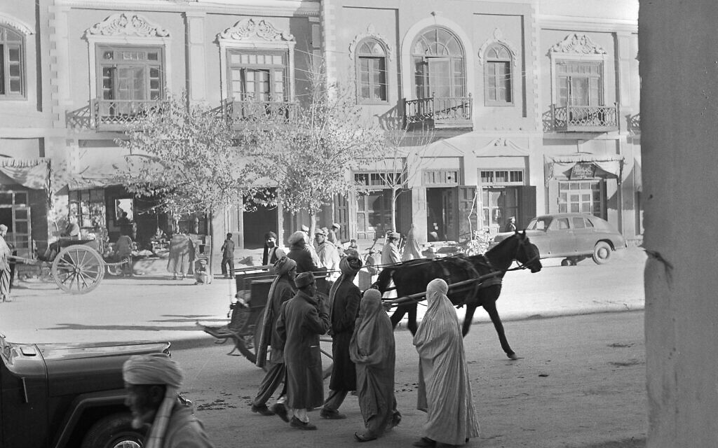 Des hommes et des femmes portant la traditionnelle burqa marchent le long d’une rue à Kaboul, en Afghanistan, en 1951. C’est à l'époque l’une des trois seules rues pavées de la capitale. (Crédit : AP Photo)