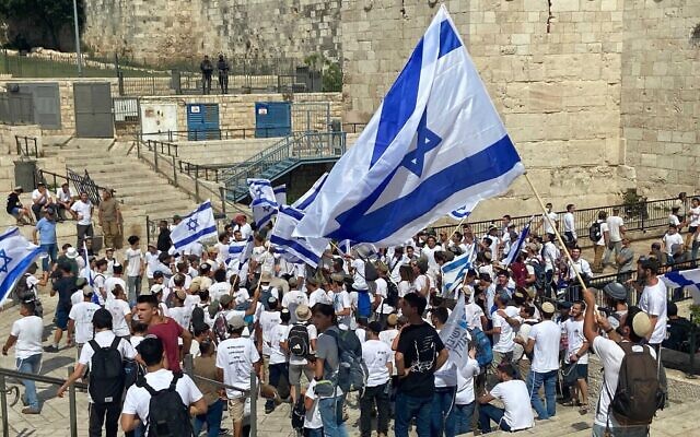 De jeunes Israéliens dansant avec des drapeaux à la porte de Damas, avant une marche nationaliste pour marquer la Journée de Jérusalem, dans la Vieille Ville de Jérusalem, le 29 mai 2022. (Crédit : Aaron Boxerman/Times of Israel)