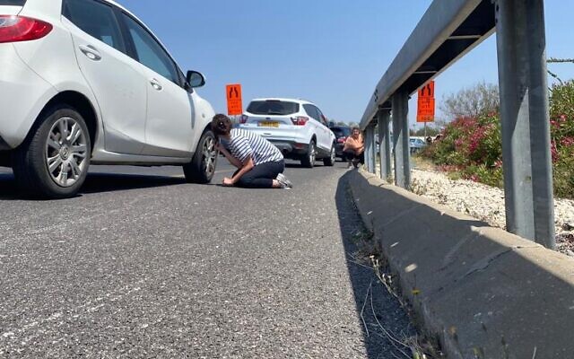Des personnes s'accroupissant sur le bord de la route alors que les sirènes d'alerte à la roquette retentissent près de Tel Aviv, le 10 mai 2023. (Crédit : Shoshana Solomon)