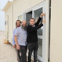 Le chef du Conseil régional de Samarie, Yossi Dagan, à droite, fixe une mezuzah à la porte de nouvelle yeshiva de Homesh, le 29 mai 2023. (Crédit : Roi Hadi)