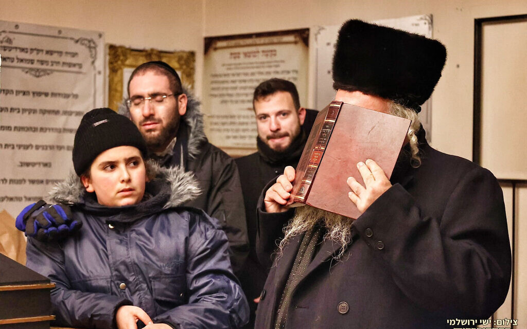 Des parents de certaines des victimes de la tragédie du mont Meron priannt en leur mémoire lors d'une visite de solidarité avec les Juifs de l'Ukraine déchirée par la guerre, le 23 décembre 2021. (Crédit : Shimon Elhadad)