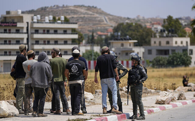 Des agents de la police des frontières empêchent des habitants d'implantations israéliennes d'entrer dans la ville palestinienne de Turmus Ayya, en Cisjordanie, le 21 juin 2023. (Crédit : Ohad Zwigenberg/AP)