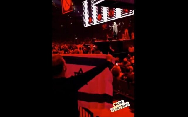 Le cinéaste Emilio Schenker arborant un drapeau israélien lors d'un concert de Roger Waters à l'O2 Arena de Londres, au Royaume-Uni, le 7 juin 2023. (Crédit : Capture d'écran de la vidéo Twitter ; utilisée conformément à l'article 27a de la loi sur le droit d'auteur)