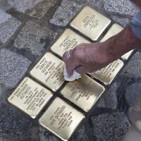 Gunter Demnig, fondateur du projet Stolpersteine, nettoie des Stolpersteine ("pierres d'achoppement") fraîchement posées en commémoration de la famille Gutmann à Feuchtwangen, en Bavière, le 30 mai 2023. (Crédit : THOMAS KIENZLE / AFP)