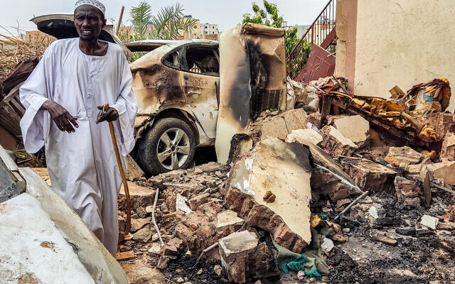 Un homme inspectant les dégâts en marchant dans les décombres d'une voiture détruite à l'extérieur d'une maison touchée par un obus d'artillerie dans le district d'Azhari, au sud de Khartoum, au Soudan, le 6 juin 2023. (Crédit : AFP)