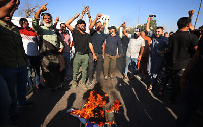 Des partisans du dirigeant musulman chiite Moqtada Sadr brûlant un drapeau LGBT devant l'ambassade de Suède à Bagdad, après qu'un Irakien vivant en Suède a brûlé un Coran, le 29 juin 2023. (Crédit : Ahmad al-Rubaye/AFP)