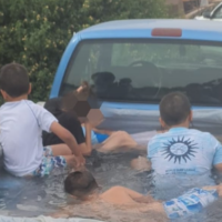 Des enfants jouent dans une piscine improvisée dans le coffre d'une camionnette en juin 2023. (Crédit : Police israélienne)