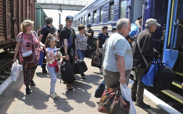 Des personnes montent à bord d'un train d'évacuation dans une gare de Kherson, en Ukraine, le 6 juin 2023, après la destruction d'un important barrage et d'une centrale hydroélectrique dans une partie du sud de l'Ukraine. (Crédit : AP Photo/Nina Lyashonok)