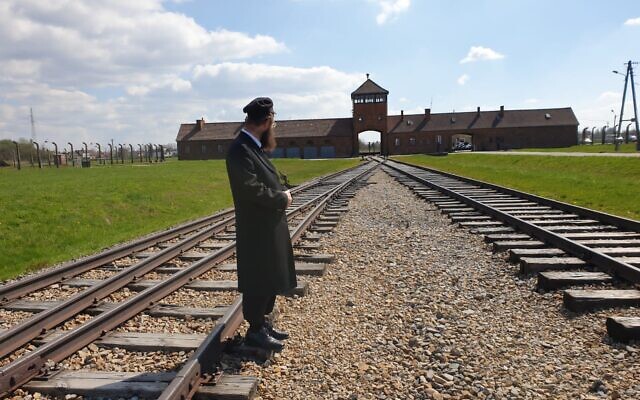 Le rabbin Israel Goldwasser, narrateur du film ‘Triumph of the Spirit', sur les rails menant, à Auschwitz-Birkenau. (Crédit :  Triumph of the Spirit)