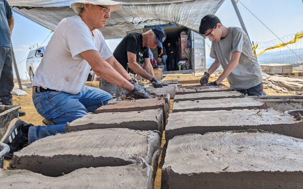 Des bénévoles fabriquent des briques à partir de moules dans le cadre des travaux de conservation à Tel Gezer, le 6 juillet 2023. (Crédit : Melanie Lidman/Times of Israel)