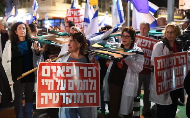 Un médecin tenant une pancarte disant "Les médecins se battent pour la vie de la démocratie", lors d'un rassemblement contre les projets de loi de réforme judiciaire du gouvernement, à Tel Aviv, le 25 février 2023. (Crédit : Gili Yaari/Flash90)