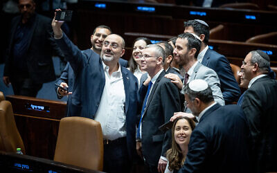 Les législateurs de la coalition se pressent autour du ministre de la Justice Yariv Levin pour prendre un selfie de célébration dans le plénum de la Knesset, alors qu'ils adoptent la première des lois de refonte judiciaire de la coalition, le 24 juillet 2023. (Crédit : Yonatan Sindel/Flash90)