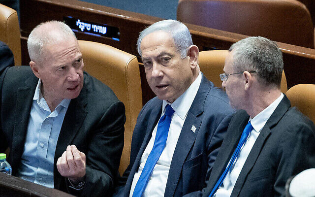 Le ministre de la Défense Yoav Gallant, à gauche, et le ministre de la Justice Yariv Levin, à droite, se disputant avant le vote de la loi du "caractère raisonnable", face au Premier ministre Benjamin Netanyahu, à la Knesset, le 24 juillet 2023. (Crédit : Yonatan Sindel/Flash90)