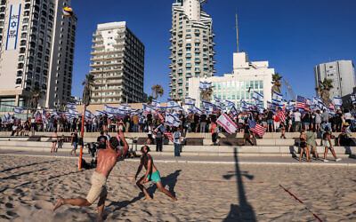 Des hommes font du beach-volley alors que des manifestants protestent contre la refonte judiciaire, devant la succursale de l'ambassade des États-Unis à Tel Aviv, le 11 juillet 2023. (Crédit : Menahem Kahana/AFP)