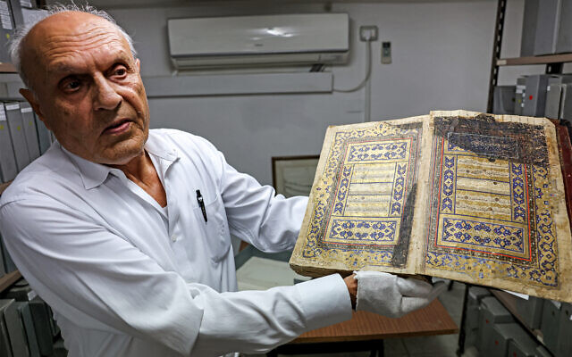 Le Palestinien Khader Salameh, bibliothécaire de la bibliothèque Khalidi, montre une copie dorée du Coran, le livre saint de l'Islam datant du 16ème siècle, dans leurs locaux dans la Vieille Ville de Jérusalem, le 20 juin 2023. (Crédit : AHMAD GHARABLI / AFP)