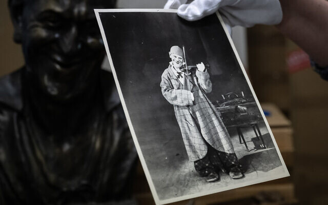 La directrice du Neues Museum Biel, Bernadette Walter, tient une photo du clown Grock à côté d'un buste de lui dans la réserve du musée, à Bienne, le 12 juin 2023. (Crédit : Fabrice COFFRINI / AFP)