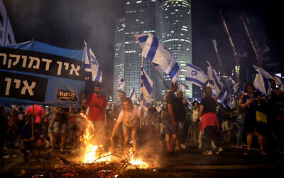 Suite à la démission du chef de la police de Tel Aviv, Amichaï Eshed, des manifestants anti-gouvernement levant des drapeaux et allumant un petit feu sur l'autoroute Ayalon à Tel Aviv, le 5 juillet 2023. (Crédit : Oren Zvi/AFP)