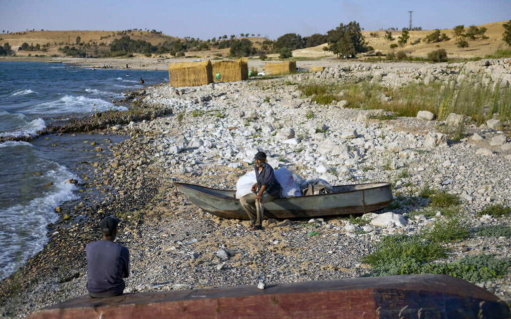 Ismail Hilal, à droite, 50 ans, qui a pris sa retraite après 37 ans de pêche, parlant à un homme assis sur un bateau sur les rives du lac Assad près du village de Jaabar dans le gouvernorat de Raqa, en Syrie, le 9 juillet 2023. (Crédit : Delil souleiman/AFP)