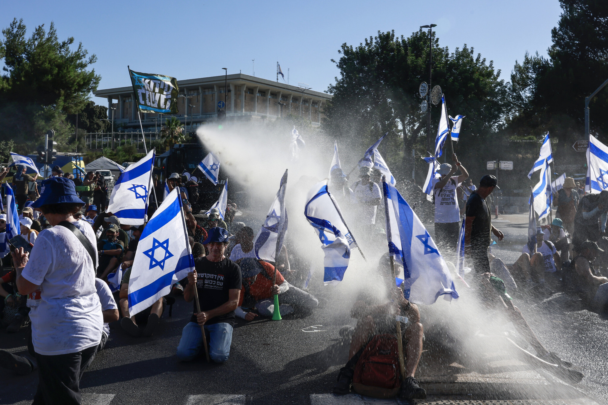Des membres des forces de sécurité israéliennes utilisent un canon à eau pour disperser des manifestants bloquant une entrée de la Knesset à Jérusalem, le 24 juillet 2023. (Menahem KAHANA / AFP)