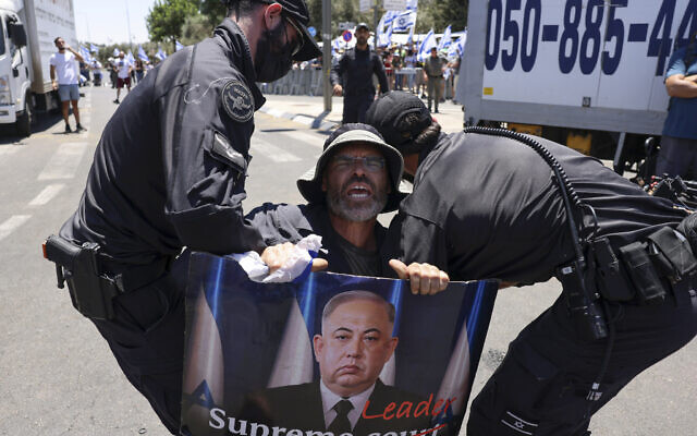 Les forces de police extirpant un manifestant qui bloque l'entrée de la Knesset, à Jérusalem, le 24 juillet 2023. (Crédit : Hazem Bader/AFP)