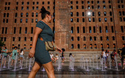 Une femme marche devant une fontaine à New York le 26 juillet 2023. (Crédit : Ed JONES / AFP)