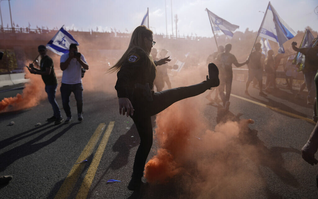 Des agents de police dispersent des manifestants contre la plan de refonte du système judiciaire qui bloquent une route à l'entrée de Jérusalem, le 11 juillet 2023. (Crédit : AP Photo/Ohad Zwigenberg)