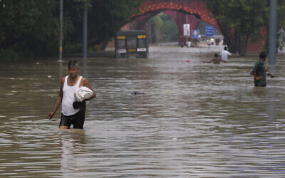 Des personnes se fraient un chemin dans une rue inondée suite aux très fortes pluies enregistrées à New Delhi, en Inde, le jeudi 13 juillet 2023. (Crédit : AP/Manish Swarup)