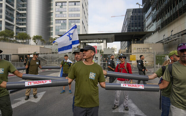 Des réservistes de l'armée israélienne, membres du groupe de protestation Frères d'armes, bloquant l'entrée du quartier général de l'armée alors qu'ils protestent contre les plans du gouvernement du Premier ministre Benjamin Netanyahu visant à remanier le système judiciaire, à Tel Aviv, le 18 juillet 2023. (Crédit : Ohad Zwigenberg/AP Photo)