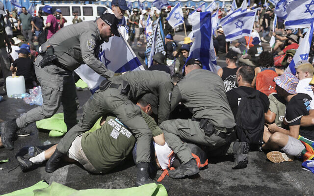 La police évacue des manifestants anti-refonte judiciaire qui bloquent une route près de la Knesset à Jérusalem, le 24 juillet 2023. (Crédit : Mahmoud Illean/AP)