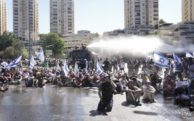 La police évacuant des manifestants anti-refonte judiciaire qui bloquent une route près de la Knesset à Jérusalem, le 24 juillet 2023. (Crédit : Mahmoud Illean/AP)